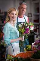 Smiling florists holding bunch of flowers in flower shop