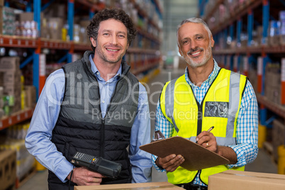 Portrait of warehouse workers standing with clipboard and barcode scanner