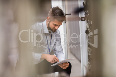 Technician using digital tablet while analyzing server