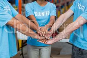 Mid section of volunteers putting hands together