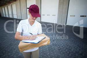 Smiling delivery woman writing on clipboard
