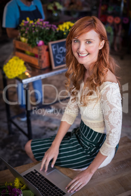 Female florist sitting and using laptop