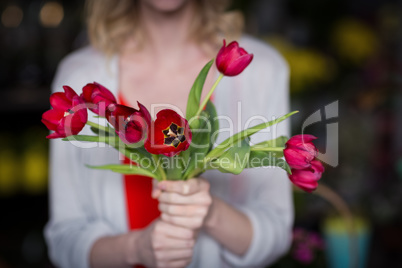 Female florist holding bunch of flower in flower shop