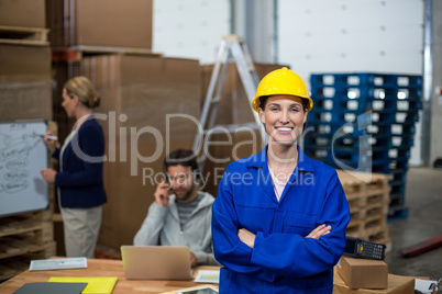 Portrait of female warehouse worker standing with arms crossed