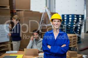Portrait of female warehouse worker standing with arms crossed