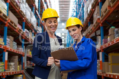 Warehouse manager and worker discussing with clipboard