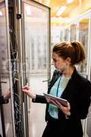 Technician holding digital tablet while examining server