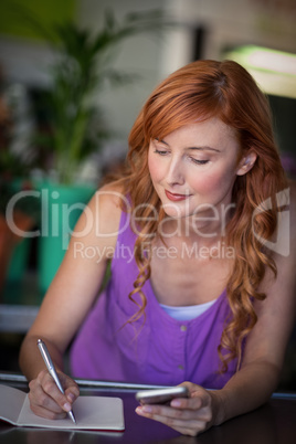 Female florist writing on notebook