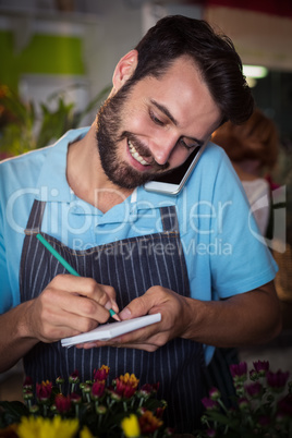 Male florist taking order on mobile phone