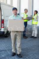 Portrait of delivery man carrying cardboard box