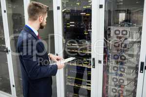 Technician holding clipboard while analyzing server