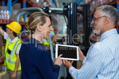 Warehouse manager and client discussing over digital tablet