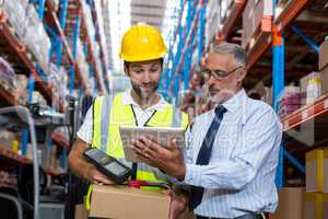 Warehouse manager with interacting male worker over digital tablet