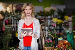 Happy female florist holding digital tablet in flower shop
