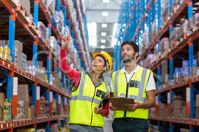 Warehouse workers discussing with clipboard while working