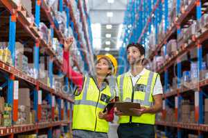 Warehouse workers discussing with clipboard while working