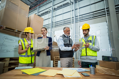 Warehouse managers and workers discussing with laptop and digital tablet