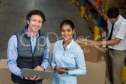 Warehouse workers using laptop and digital tablet