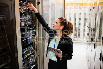 Technician holding digital tablet while examining server