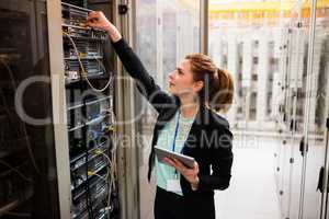 Technician holding digital tablet while examining server