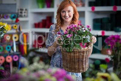Happy female florist holding basket of flowers