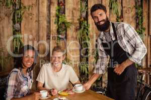 Waiter serving a cup of coffee to customer