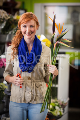 Smiling female florist trimming flower stem
