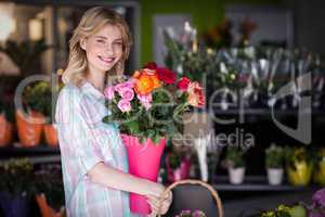 Happy female florist holding flower vase