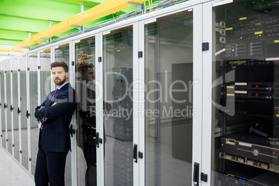 Technician standing with arms crossed in a server room