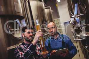 Manufacturer inspecting beer in tube with worker