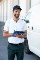 Portrait of delivery man holding a clipboard next to his van