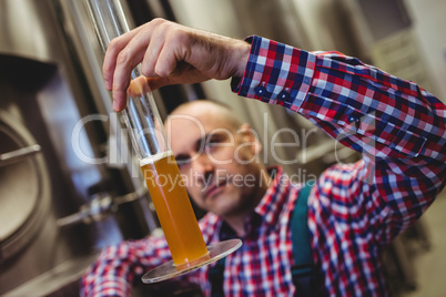 Owner examining beer in glass tube