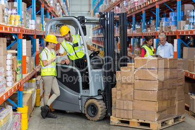 Male and female worker discussing over clipboard