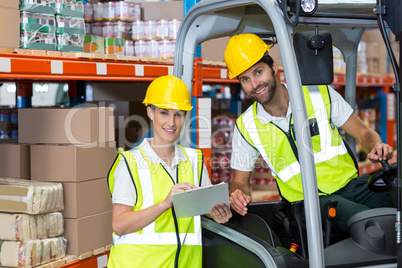 Male and female worker discussing over clipboard