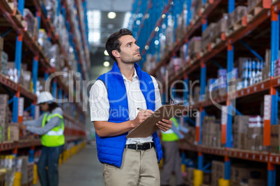 Warehouse worker writing on clipboard