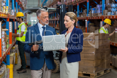 Warehouse manager and client using laptop