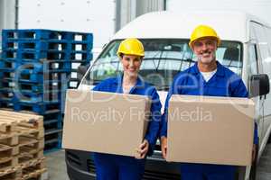 Portrait of delivery workers carrying cardboard box