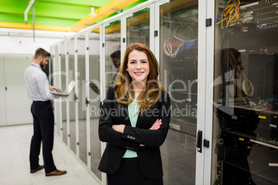 Technician standing with arms crossed in a server room