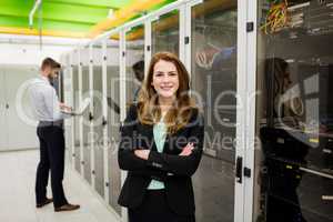 Technician standing with arms crossed in a server room
