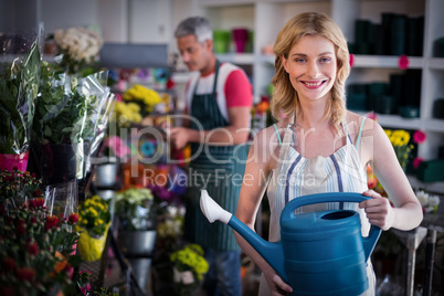 Happy female florist watering flowers