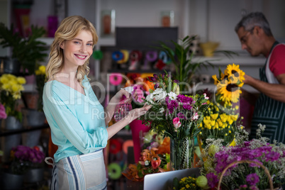 Smiling florist spraying water on flowers in flower shop