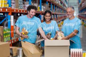 Three volunteers packing eatables in cardboard box