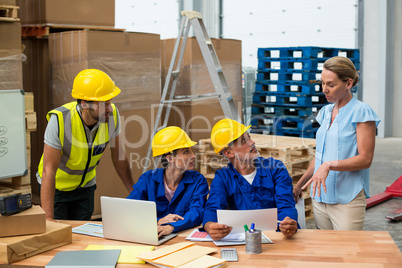 Warehouse workers discussing with manager