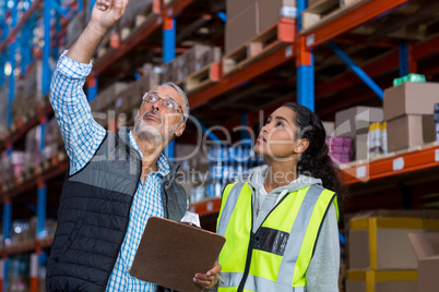Warehouse workers discussing with clipboard while working