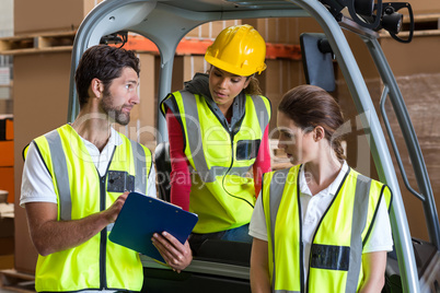 Warehouse workers talking with forklift driver