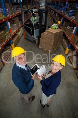 Warehouse manager and client holding digital tablet and clipboard