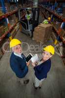 Warehouse manager and client holding digital tablet and clipboard