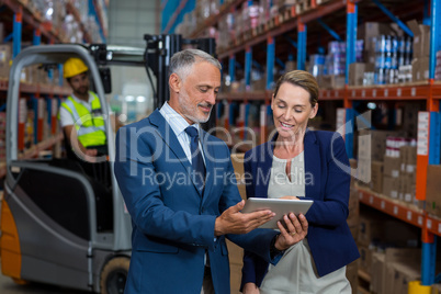 Warehouse manager and client discussing over digital tablet