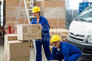 Delivery workers unloading cardboard boxes from pallet jack