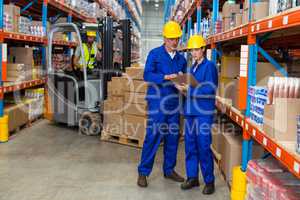 Warehouse workers discussing with clipboard